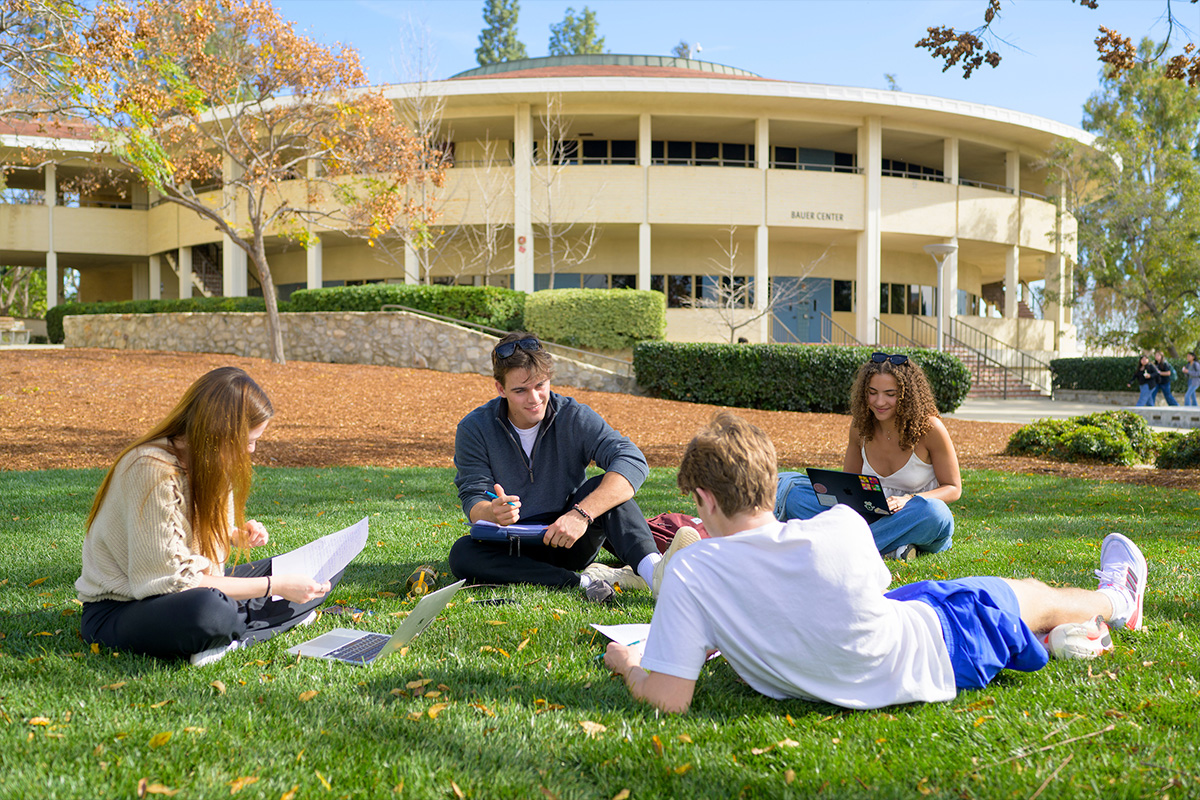 Students sitting on the grass outside Bauer Center.