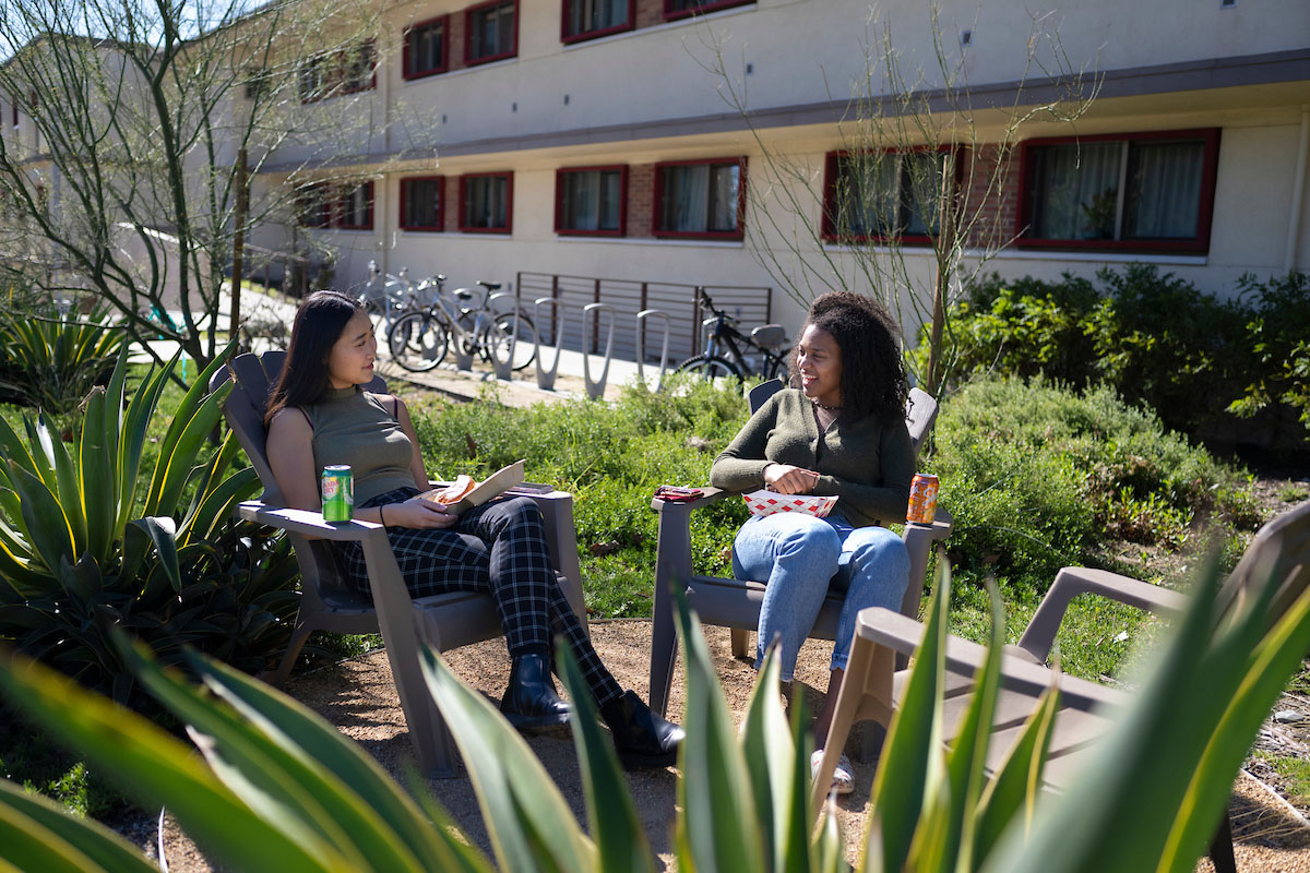 Two female students seated in an outdoor space in Mid Quad.