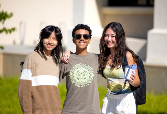 Three students smiling and posing together.