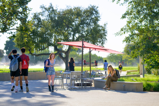 Students around an umbrella table on campus.