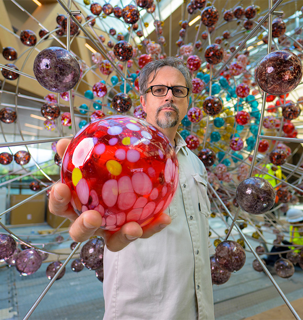 Damián Ortega holding glass orb.
