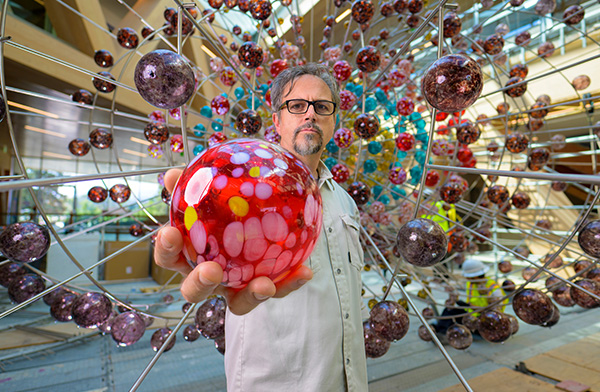 Damián Ortega holding glass orb.