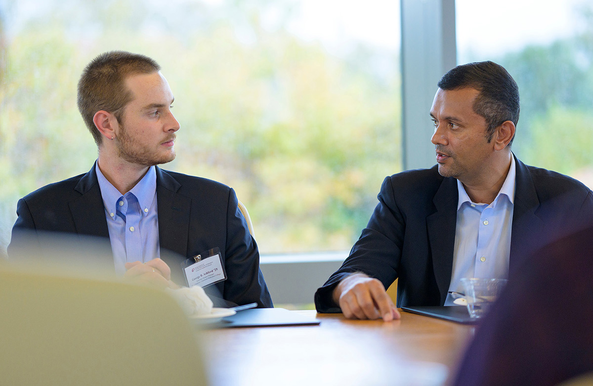 A student speaking with a Rose Institute board member at a breakfast event.