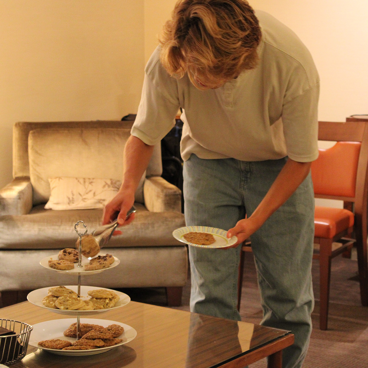A student placing cookies on a plate.