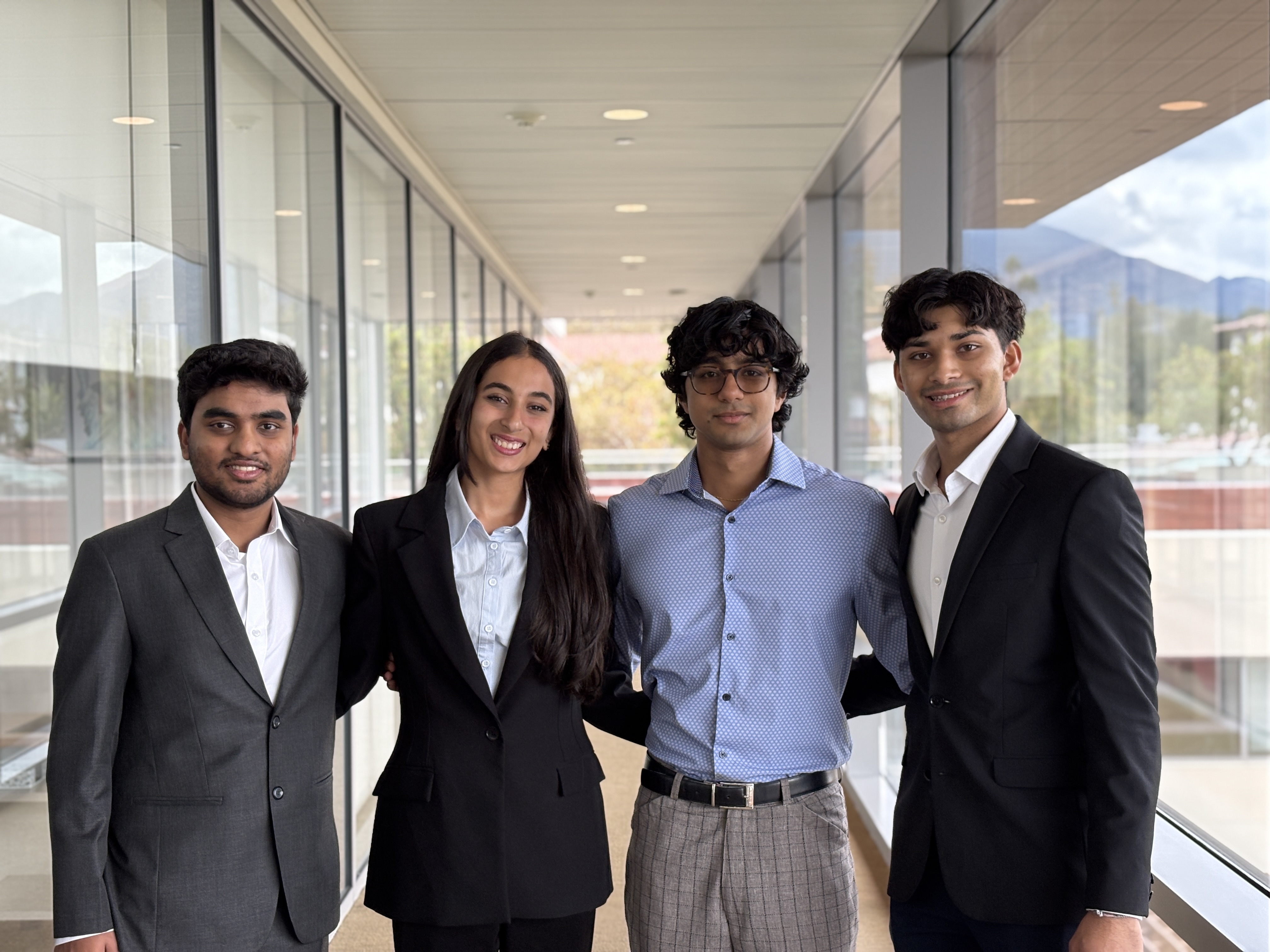 Four students in business attire pose, smiling, after winning the 2025 RLCIE Venture Capital program pitch competition.
