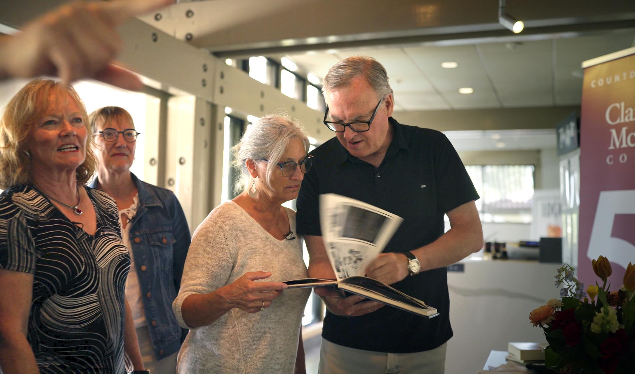 Class of 1980 classmates looking at yearbook