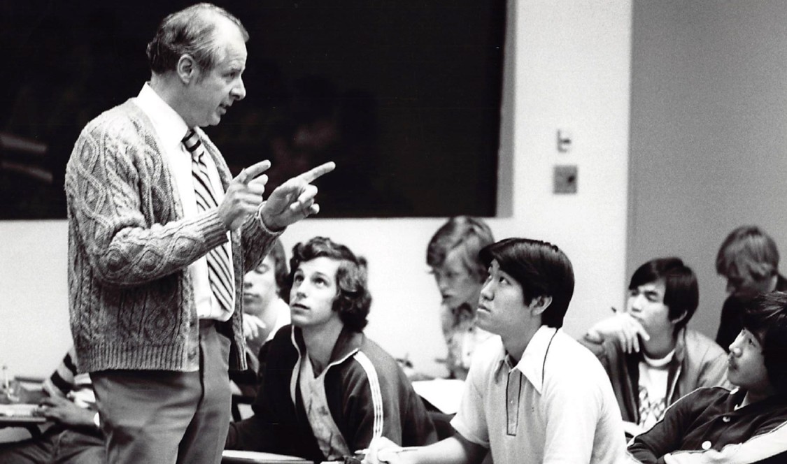 In a black and white photo, Professor John Ferling addresses his seated students during class.