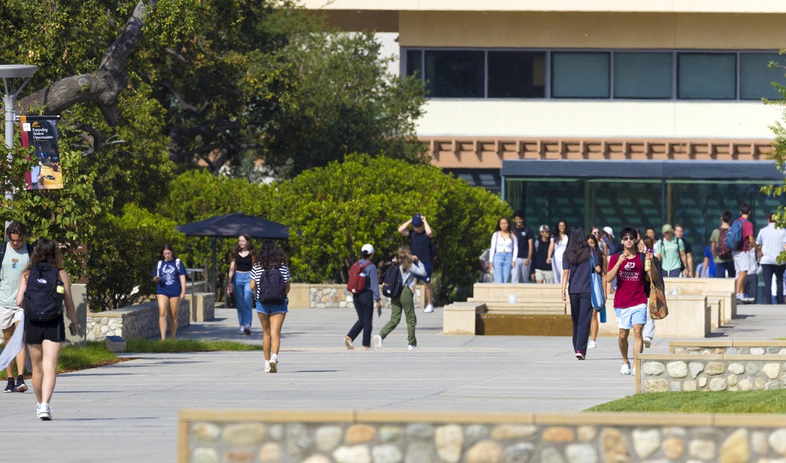 Students walking down campus in front of the Kravis Center.