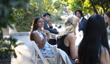 Students in cocktail dresses and suits enjoy open dialogue at the Ath head table, held outdoors during the COVID-19 pandemic.