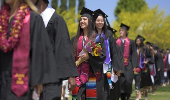 About-to-be graduates walk in a single file procession to the Commencement tent in 2022.