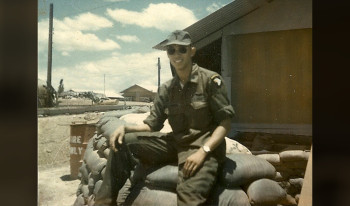 Russ as a young man in the service, seated on stacked bags of sand.