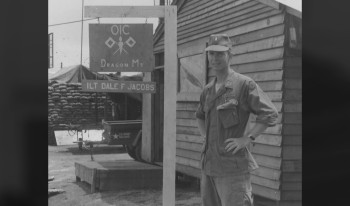 Black and white photo of Dale Jacobs '66 in fatigues outside his camp.