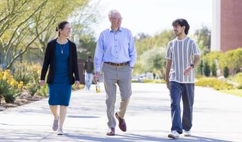 President Will Dudley and wife Dr. Carola Tanna walking with student on campus