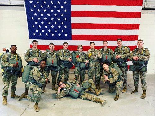 John with his squad mates in front of a U.S. flag.