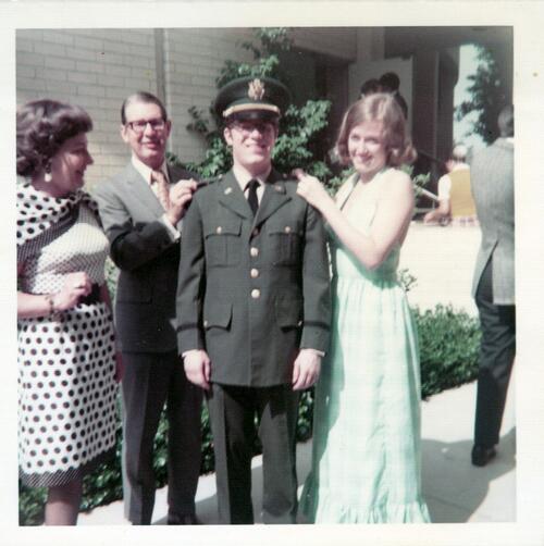Man in military uniform with girl in green dress and parents. 