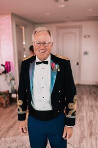 Man in black tuxedo top and blue bottoms at military service.