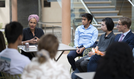 Zadie Smith and students seated outside with patio tables and chairs.