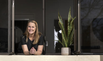 DT leans out of the open window in her office next to her snake plant.