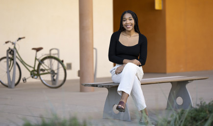 Courtney Hooks ’23 sits on a bench on campus, facing Gann Quadrangle.