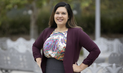 Portrait of CMC Prof. Jennifer Feitosa with her arms akimbo on campus.