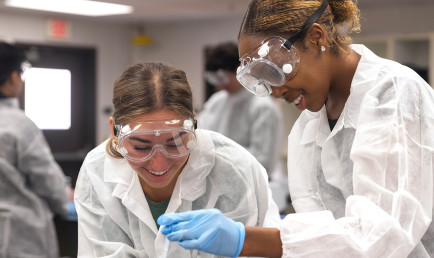 Two students working with tubs in a lab.