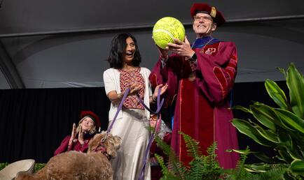 Pres. Chodosh holding large tennis ball with Priya Junnar and Theo