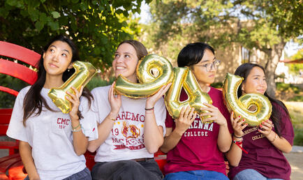 Four students holding 1946 balloons