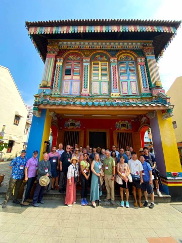 Worldmeet group stands in front of colorful building. 