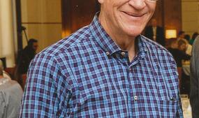 Man with blond short hair wearing glasses and blue with red flannel.