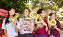 Four students holding 1946 balloons